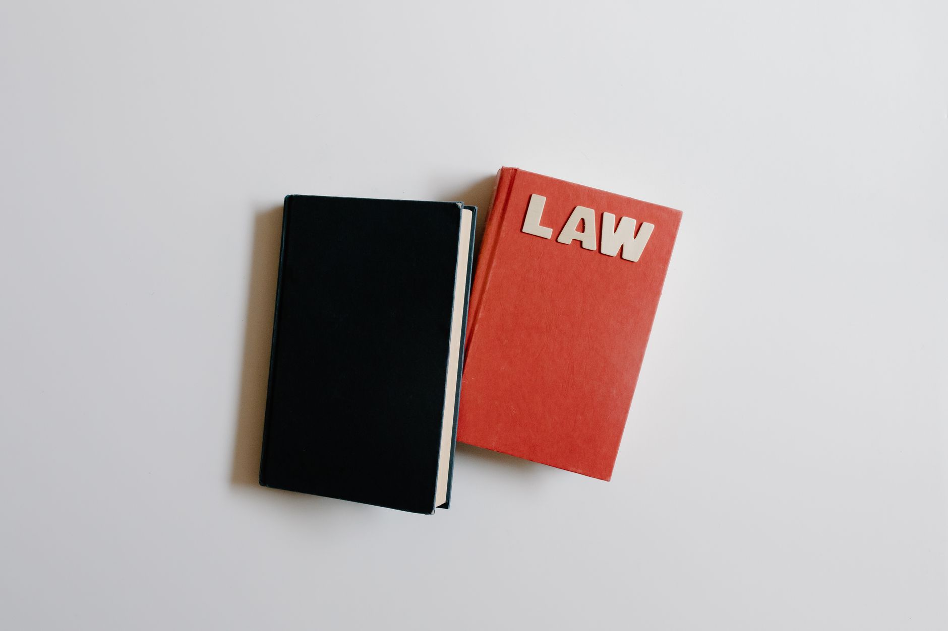 Ilustrasi hukum dengan simbol keadilan (timbangan), gavel, dan buku undang-undang di atas meja kayu.